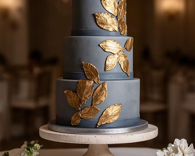 Tarta de boda de fondant azul grisáceo con hojas doradas y decoración artesanal en Murcia